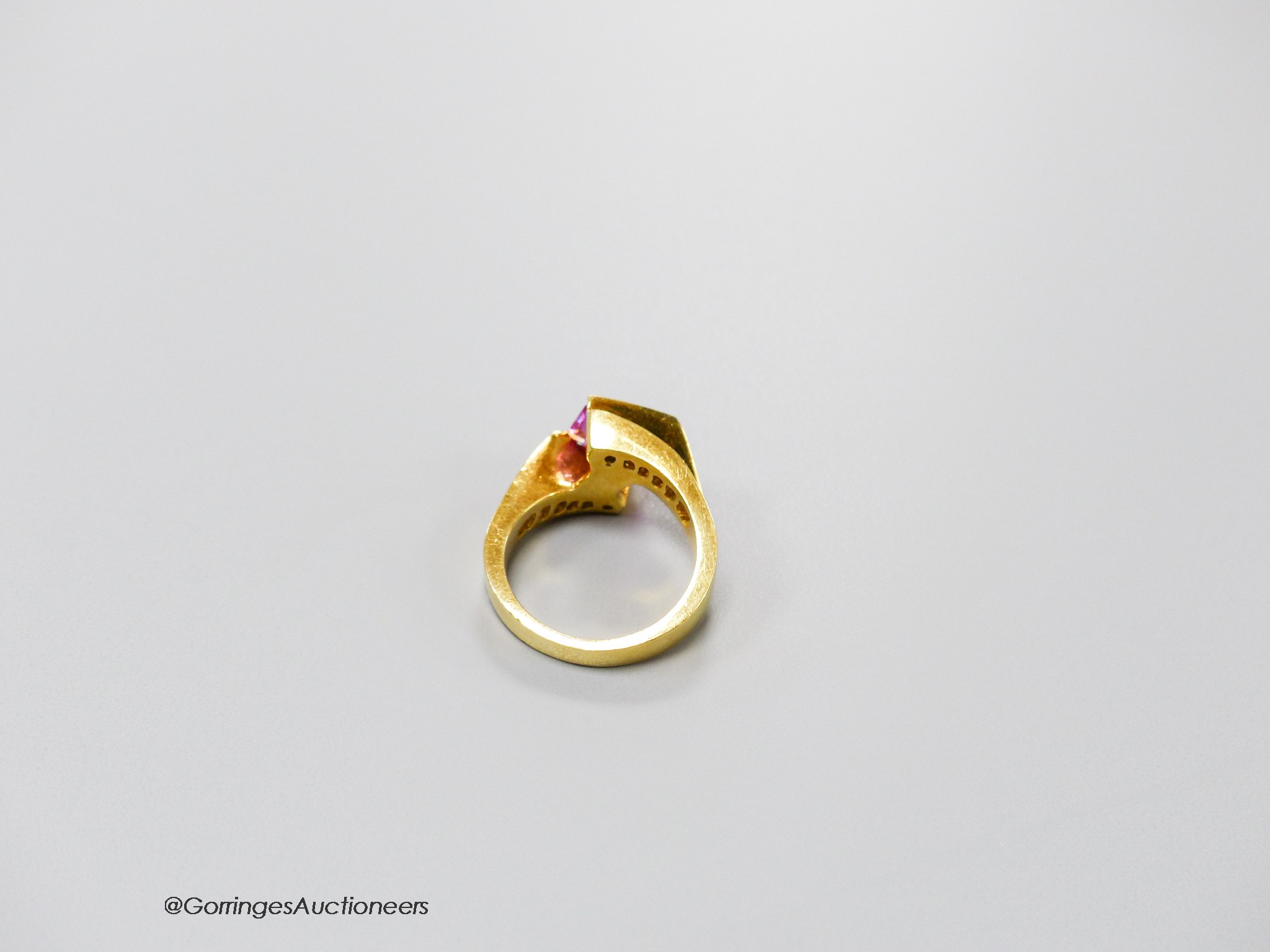 A modern 18k gold, emerald cut pink sapphire set dress ring, with graduated baguette cut diamond set shoulders, size M, gross weight 8.6 grams.